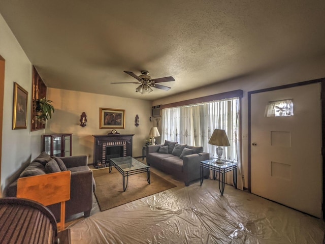 living room with a textured ceiling, a brick fireplace, and ceiling fan