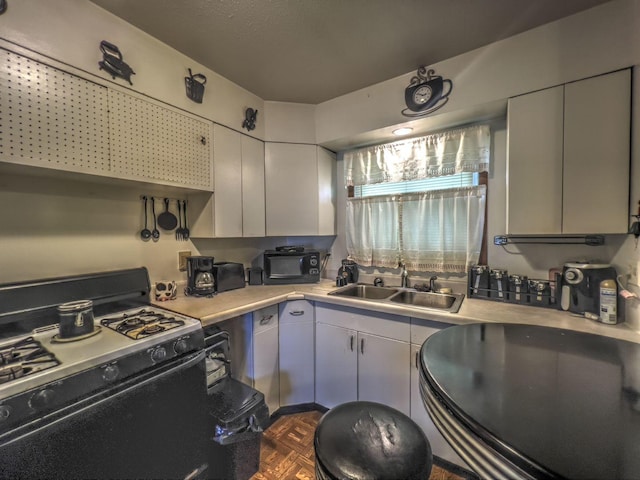 kitchen featuring dark parquet flooring, sink, and black gas range