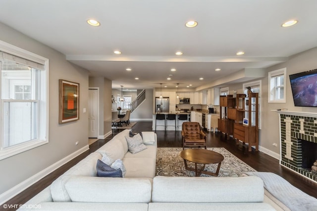 living room with dark hardwood / wood-style floors, a fireplace, and plenty of natural light