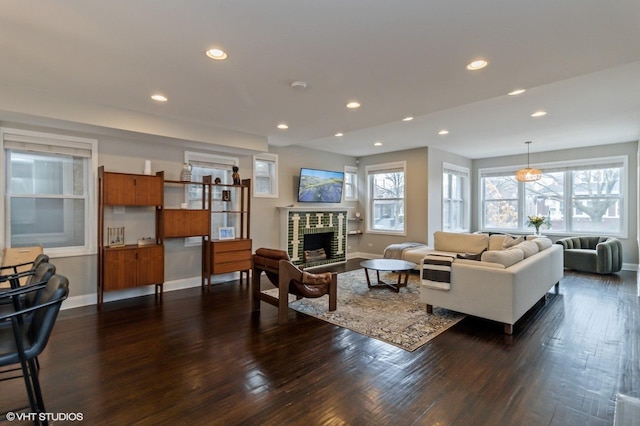 living room with a brick fireplace and dark hardwood / wood-style flooring