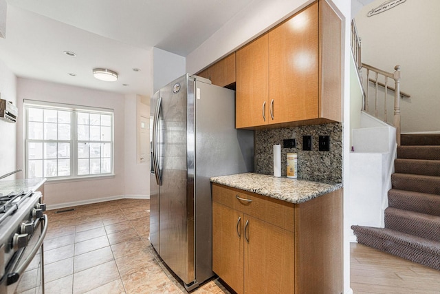 kitchen with stainless steel appliances, light stone counters, and decorative backsplash