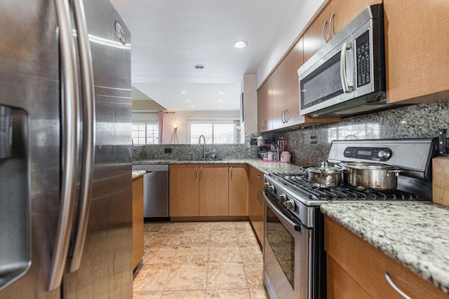 kitchen with sink, light stone counters, tasteful backsplash, and appliances with stainless steel finishes