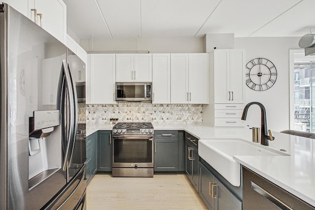 kitchen featuring gray cabinets, white cabinetry, appliances with stainless steel finishes, and sink