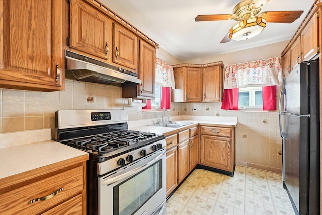 kitchen featuring sink, stainless steel range with gas stovetop, a healthy amount of sunlight, and black fridge