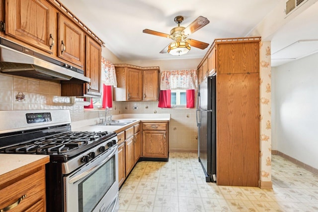 kitchen featuring black refrigerator, sink, stainless steel gas range, and a healthy amount of sunlight