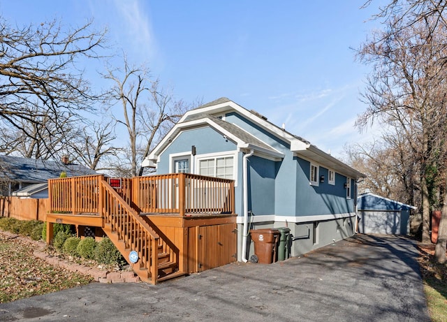 view of front of property featuring a garage, a deck, and an outbuilding