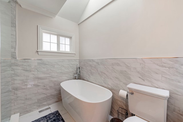 bathroom featuring toilet, tile walls, vaulted ceiling, crown molding, and a bathtub