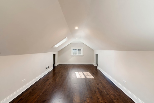 additional living space with vaulted ceiling with skylight and dark hardwood / wood-style floors