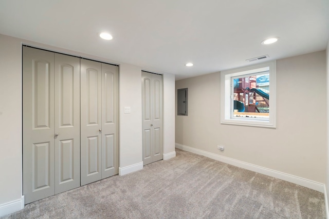 unfurnished bedroom featuring light carpet, electric panel, and two closets