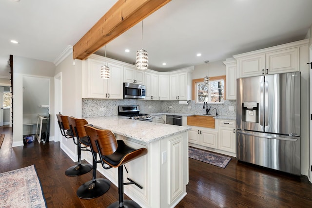 kitchen with kitchen peninsula, beamed ceiling, light stone countertops, appliances with stainless steel finishes, and white cabinets