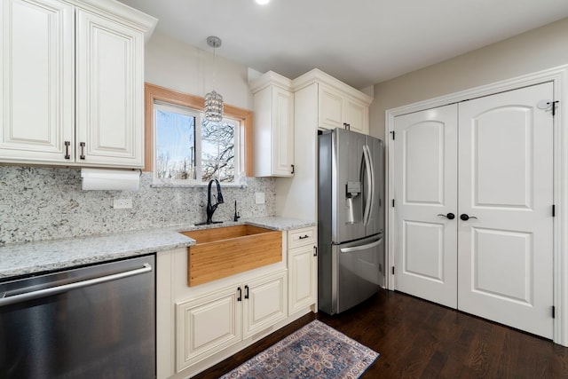 kitchen with decorative light fixtures, tasteful backsplash, sink, appliances with stainless steel finishes, and light stone counters