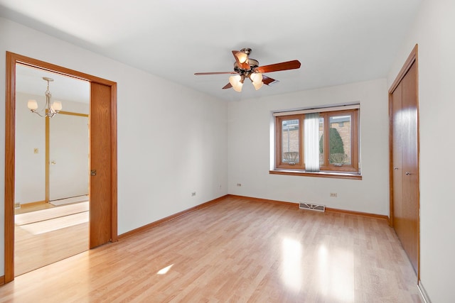 unfurnished bedroom featuring ceiling fan with notable chandelier and light hardwood / wood-style floors