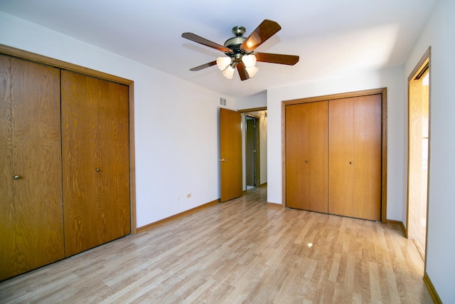 unfurnished bedroom featuring light wood-type flooring, ceiling fan, and two closets