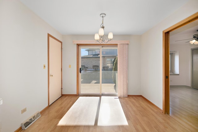 empty room featuring ceiling fan with notable chandelier and light wood-type flooring