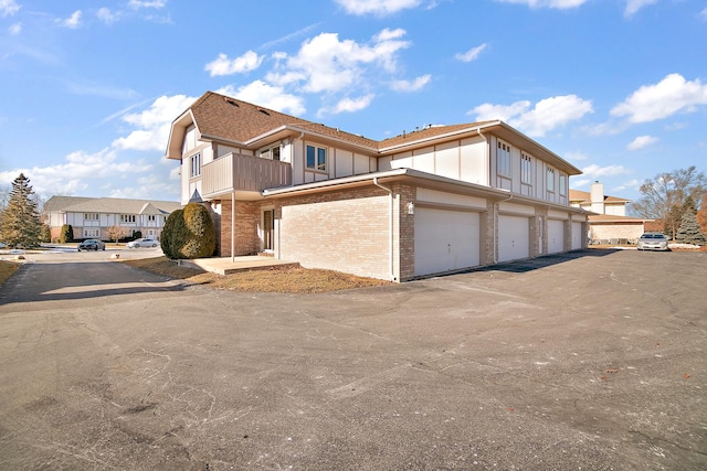 view of side of home with a garage and a balcony