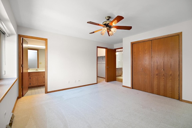 unfurnished bedroom with ceiling fan, light colored carpet, connected bathroom, and sink