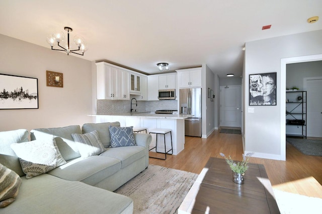 living room featuring sink, a notable chandelier, and light wood-type flooring