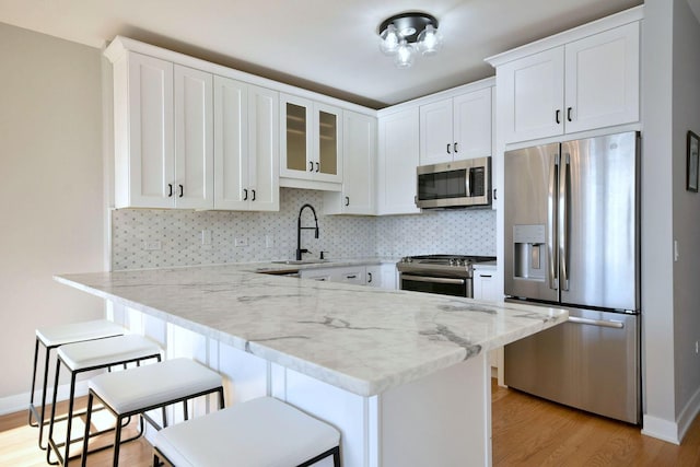 kitchen featuring sink, stainless steel appliances, a kitchen breakfast bar, and white cabinets