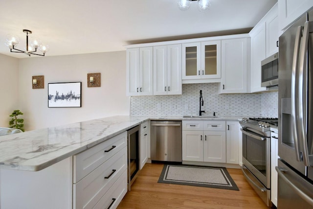 kitchen featuring white cabinetry, stainless steel appliances, kitchen peninsula, and sink