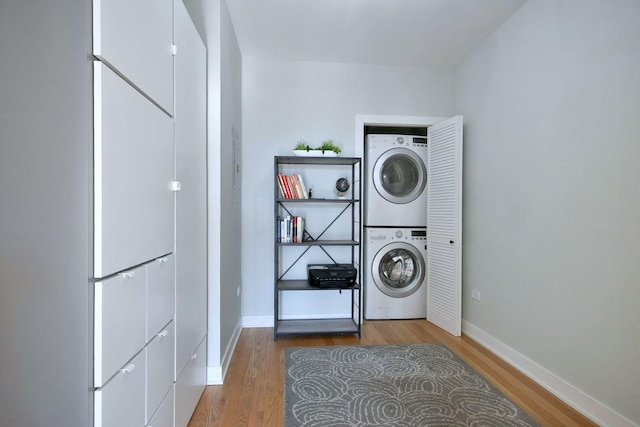 laundry area featuring stacked washer / drying machine and hardwood / wood-style floors