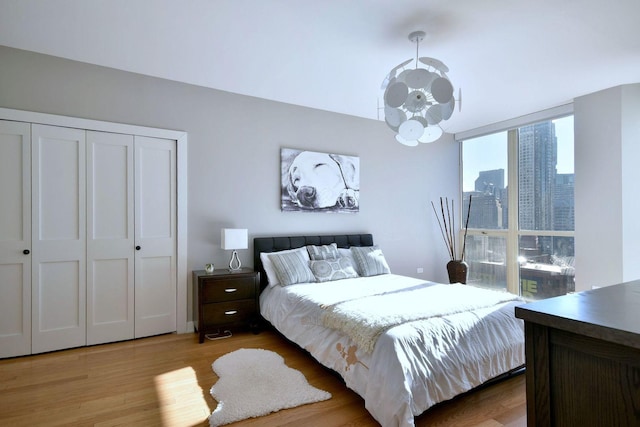 bedroom with expansive windows, a notable chandelier, and light wood-type flooring