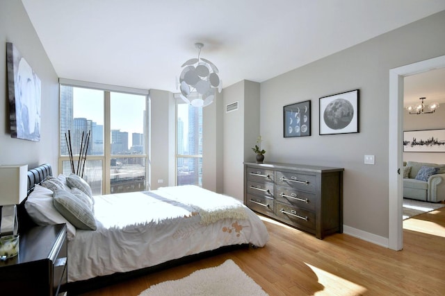 bedroom with floor to ceiling windows, a chandelier, and light hardwood / wood-style flooring