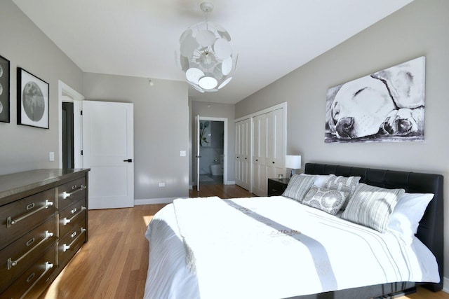 bedroom with an inviting chandelier, light hardwood / wood-style flooring, and a closet