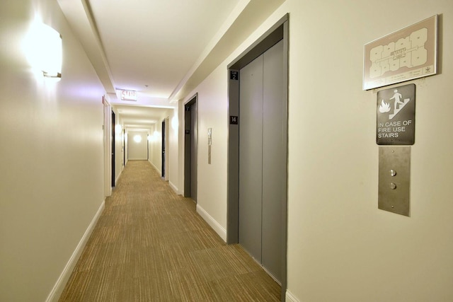 hallway with elevator and carpet flooring