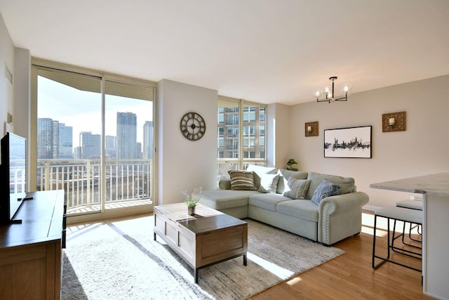 living room with a wall of windows, a chandelier, and light wood-type flooring