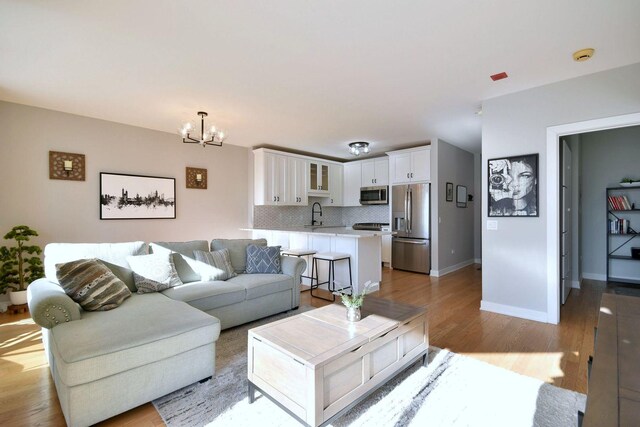 living room featuring sink, a notable chandelier, and light hardwood / wood-style flooring