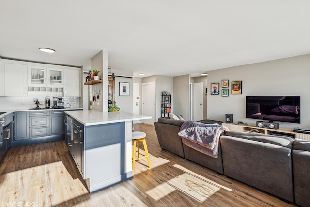 kitchen with white cabinetry, a barn door, a breakfast bar area, tasteful backsplash, and light hardwood / wood-style flooring