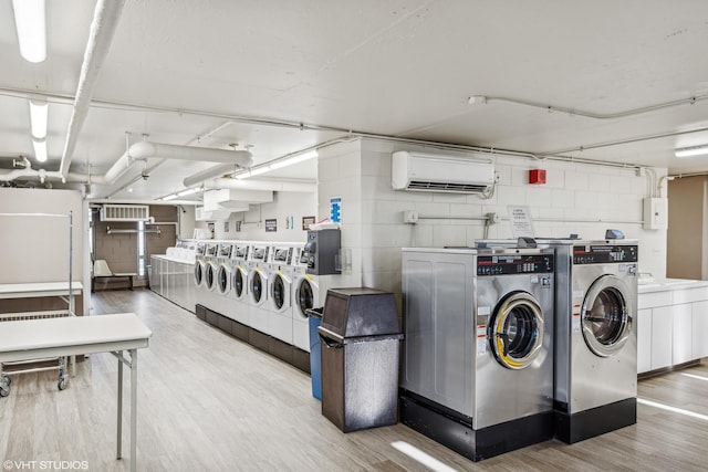 laundry area featuring separate washer and dryer, light wood-type flooring, and a wall mounted air conditioner