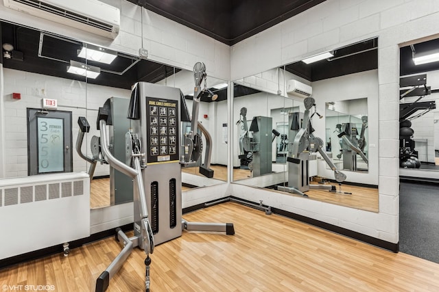 gym with radiator, hardwood / wood-style floors, and a wall mounted air conditioner