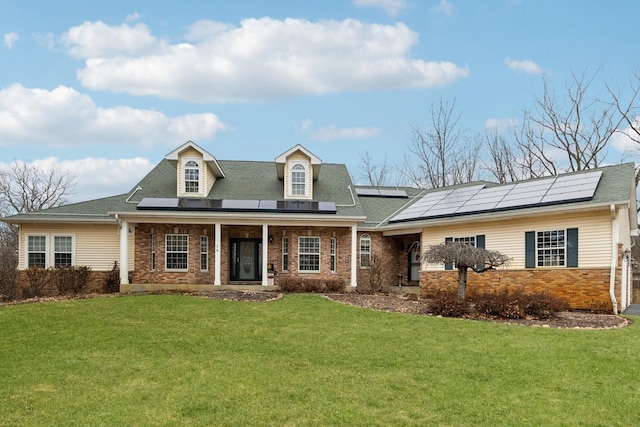 view of front of house with a porch, a front lawn, solar panels, and brick siding