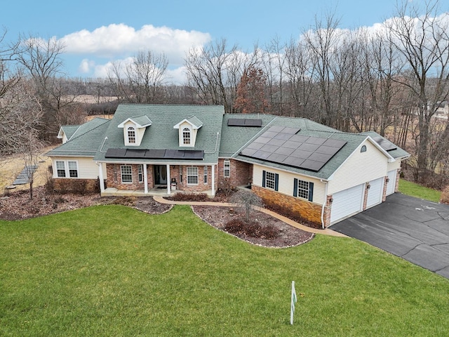 view of front of house with covered porch, driveway, a front yard, and solar panels