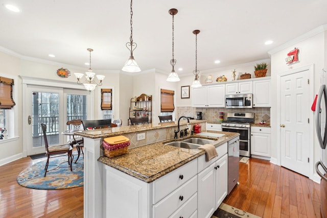 kitchen with wood-type flooring, appliances with stainless steel finishes, decorative backsplash, and a sink