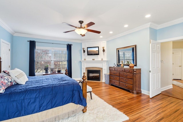 bedroom with recessed lighting, a fireplace, baseboards, light wood-style floors, and crown molding