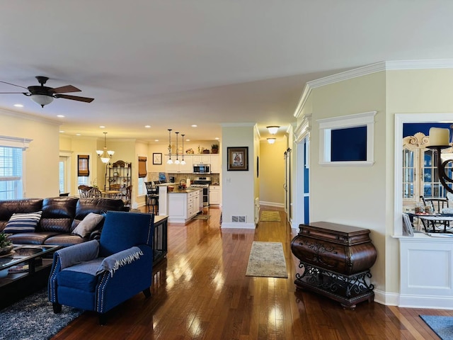 living room with crown molding, visible vents, dark wood-style flooring, recessed lighting, and ceiling fan with notable chandelier