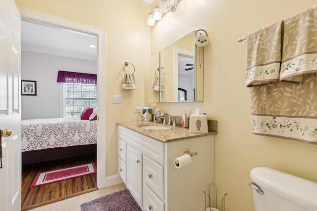 ensuite bathroom featuring toilet, connected bathroom, vanity, tile patterned flooring, and baseboards