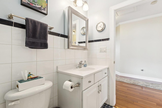 half bathroom with toilet, ornamental molding, wood finished floors, vanity, and tile walls