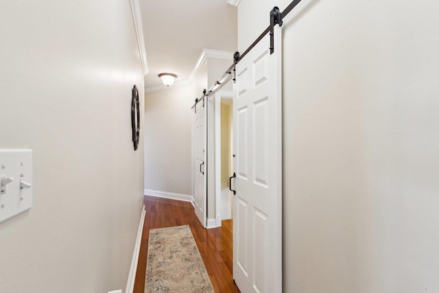 hallway featuring crown molding, a barn door, dark wood-style flooring, and baseboards