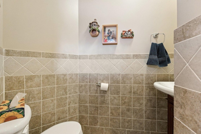 bathroom with a wainscoted wall, tile walls, and toilet