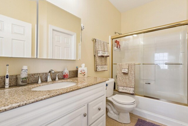 full bathroom with toilet, tile patterned floors, bath / shower combo with glass door, and vanity