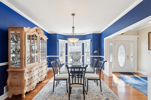 dining room with baseboards, visible vents, ornamental molding, and wood finished floors