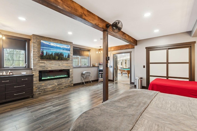 bedroom featuring a stone fireplace, recessed lighting, baseboards, beamed ceiling, and dark wood-style floors