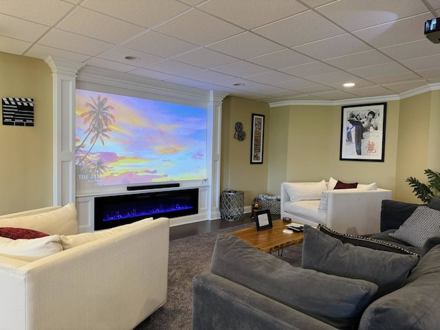 living room with crown molding, a paneled ceiling, a glass covered fireplace, and wood finished floors