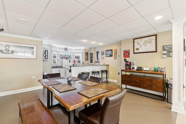 dining space featuring a paneled ceiling and baseboards