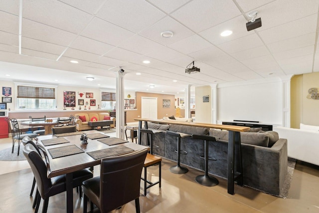 dining area featuring concrete floors, decorative columns, and a paneled ceiling