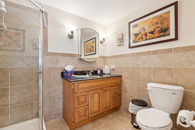 bathroom featuring vanity, wainscoting, toilet, tile walls, and a stall shower