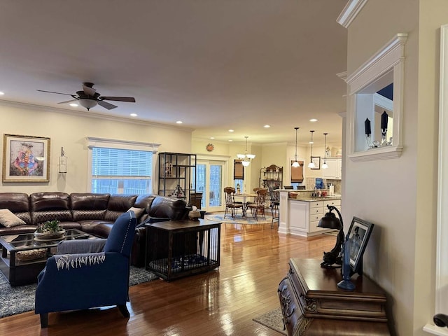 living room featuring crown molding, light wood-style flooring, and ceiling fan